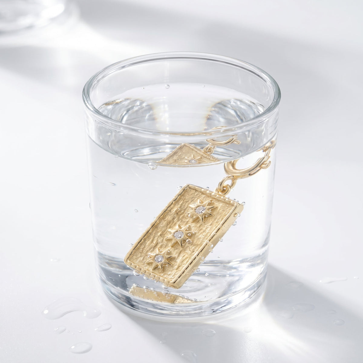 Charm estrella para collar bañado en oro de 18K en un vaso de agua