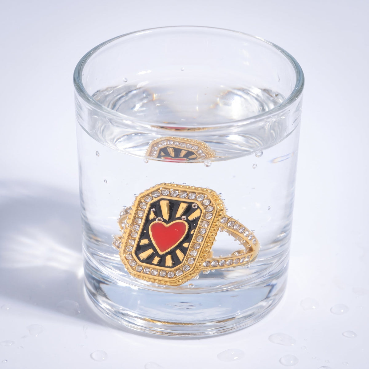 Anillo corazón rojo vintage bañado en oro de 18K en un vaso de agua