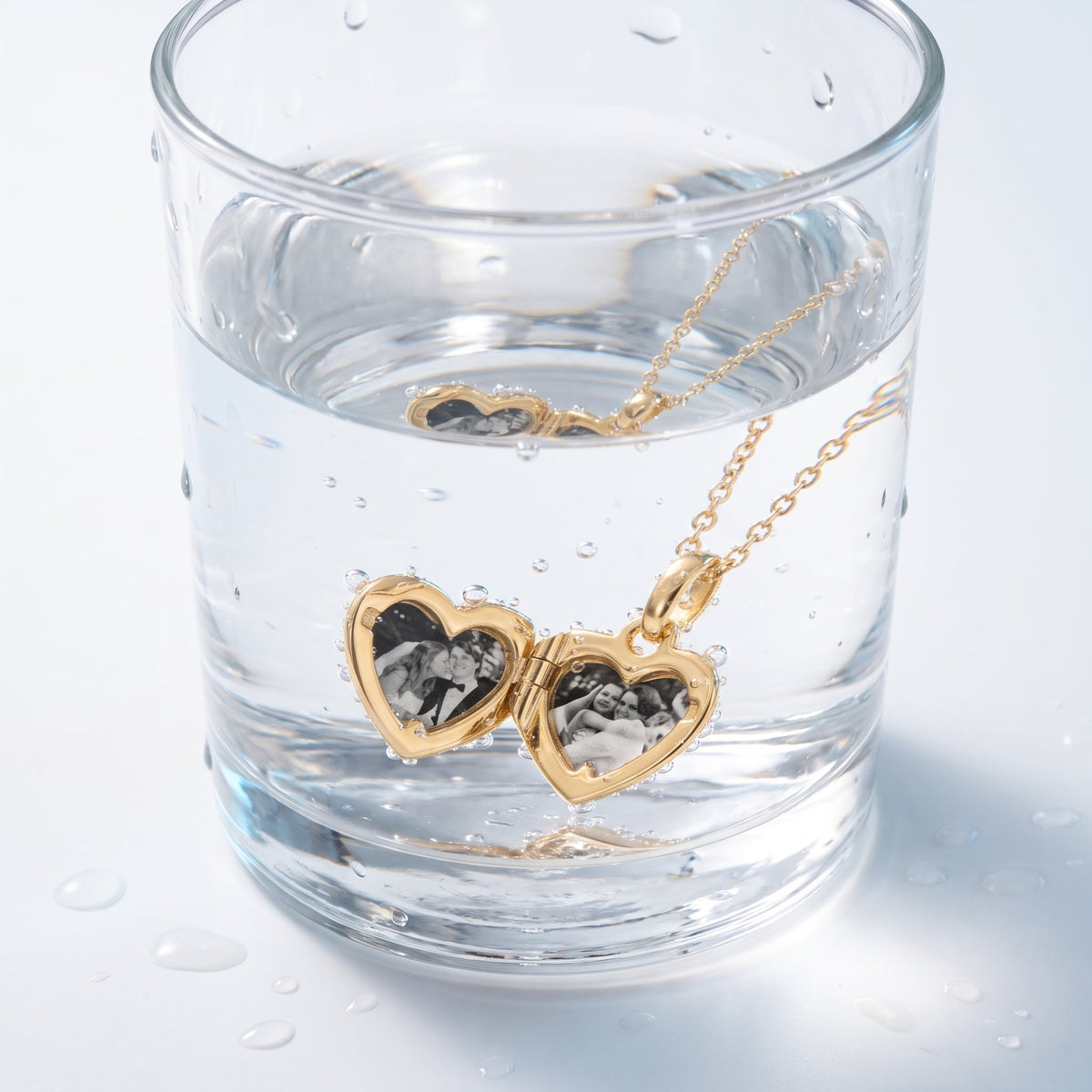 Collar medallón portafotos bañado en oro de 18K en un vaso de agua