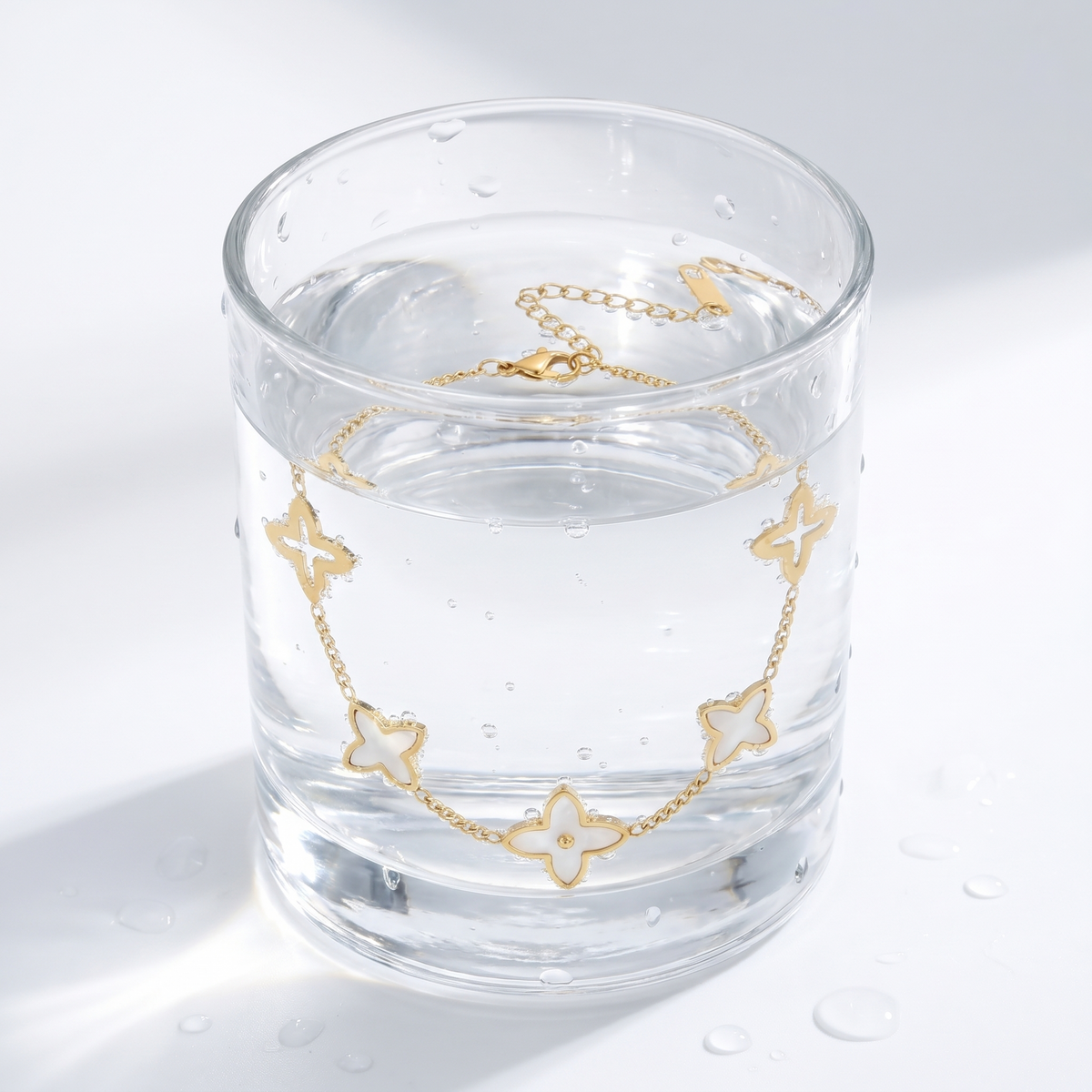 Bracciale quadrifoglio madreperla placcato oro 18K in un bicchiere d'acqua