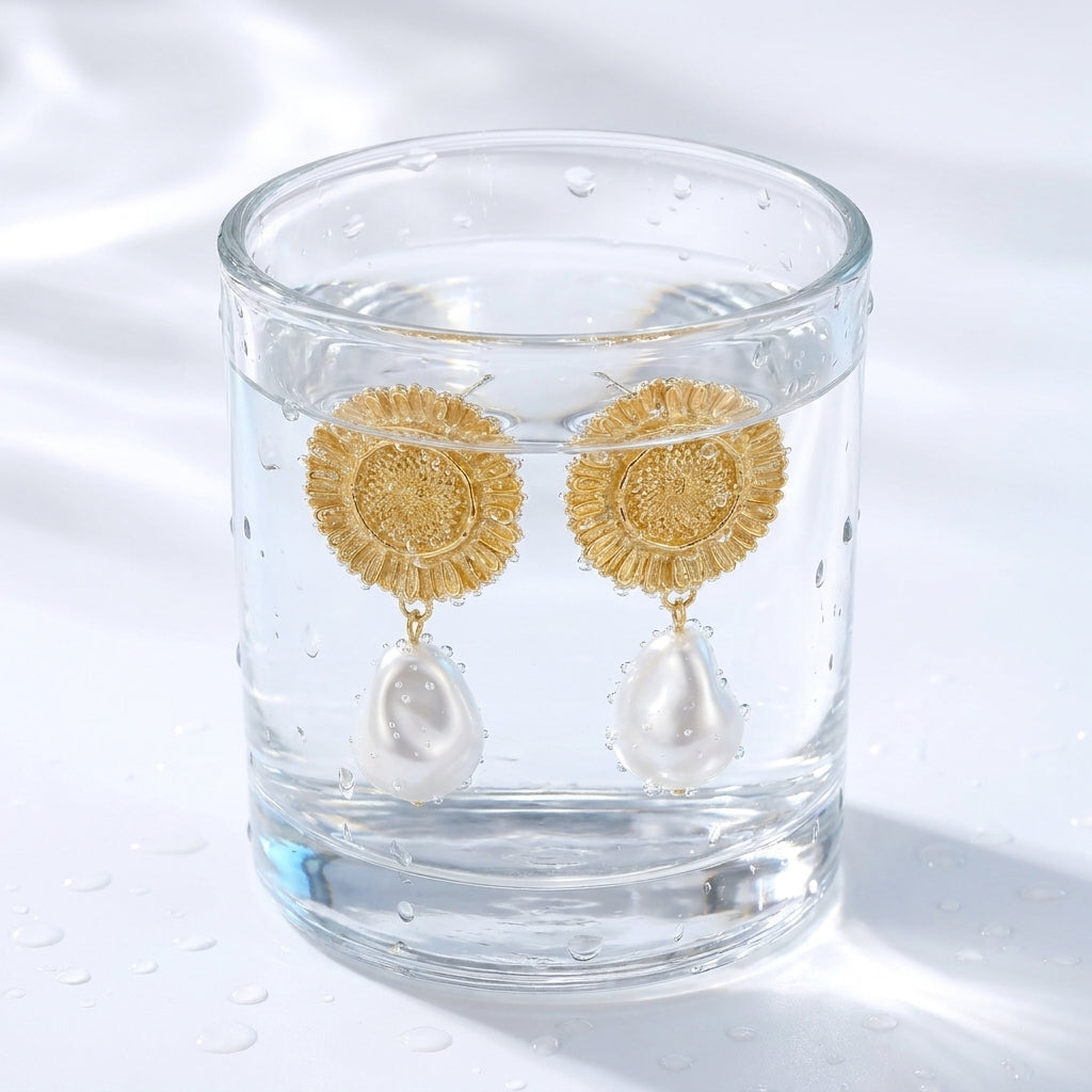 Pendientes colgantes de sol y perla bañados en oro de 18K en un vaso de agua