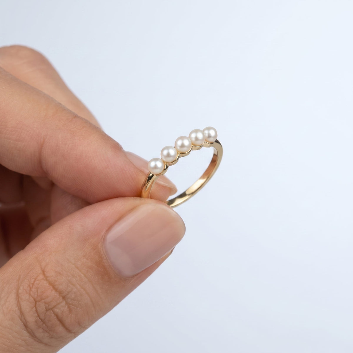 Anillo fino con 5 perlitas bañado en oro de 18K sostenido entre los dedos, para ver el tamaño real