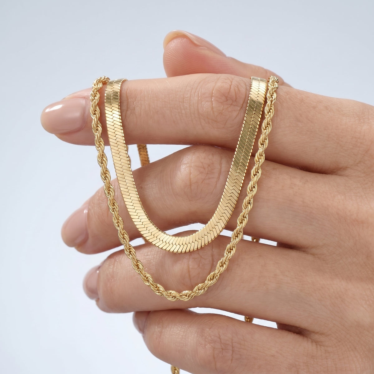 Collar doble espiga bañado en oro de 18K sostenido entre los dedos, para ver el tamaño real