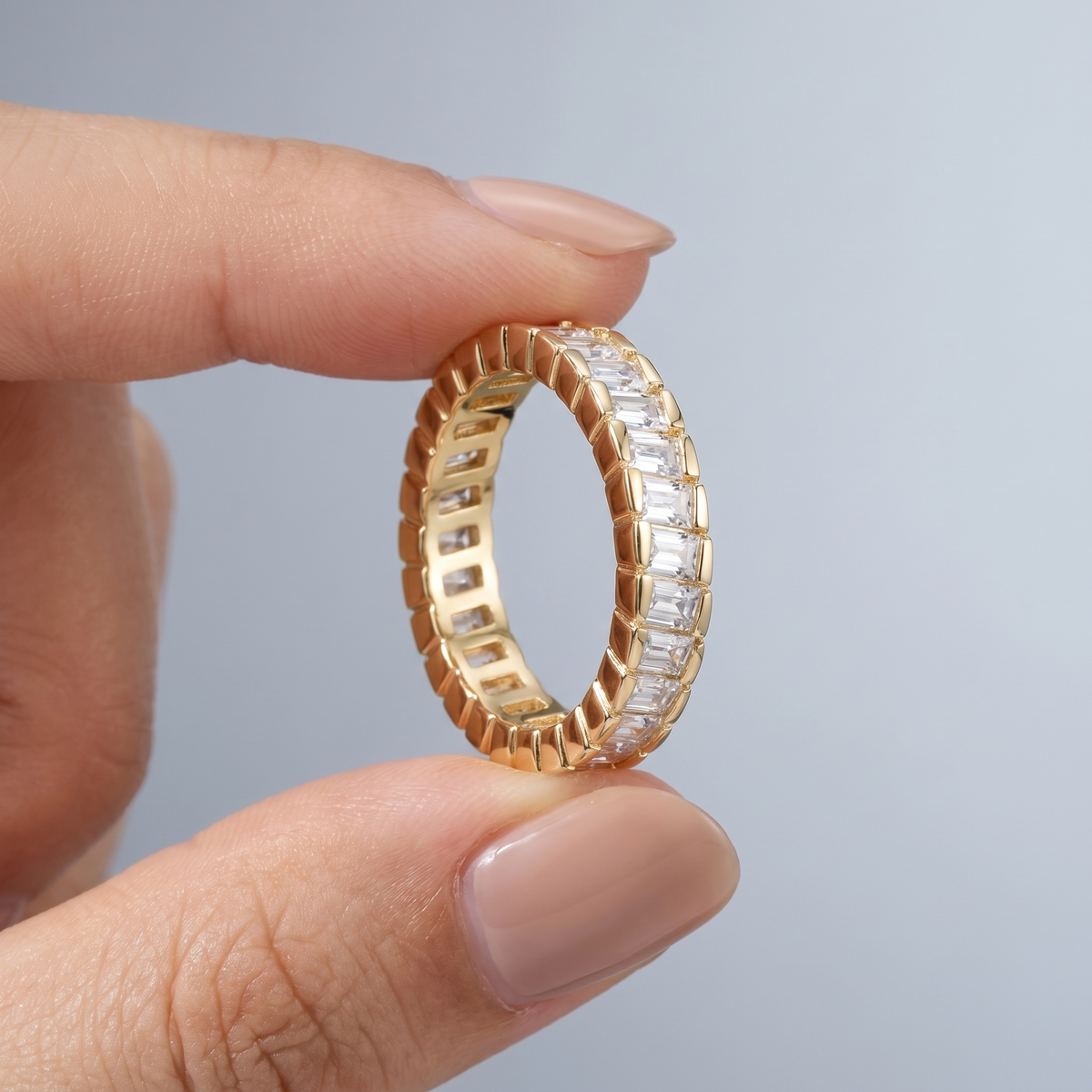 Anillo eternity con circonitas baguette bañado en oro de 18K sostenido entre los dedos, para ver el tamaño real
