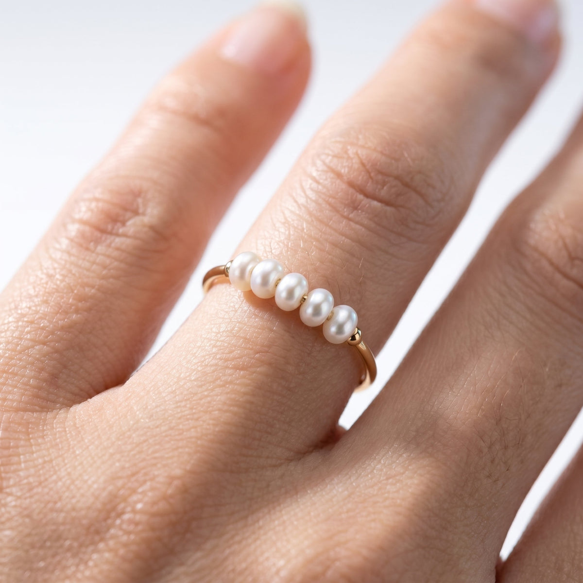 Anillo fino con 5 perlitas bañado en oro de 18K puesto, primer plano