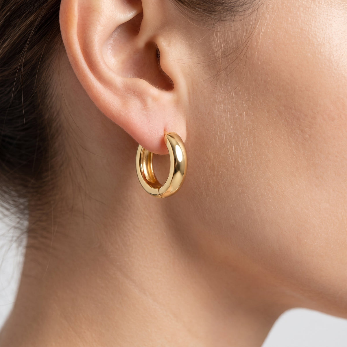 Pendientes huggie lisos bañados en oro de 18K puestos, primer plano
