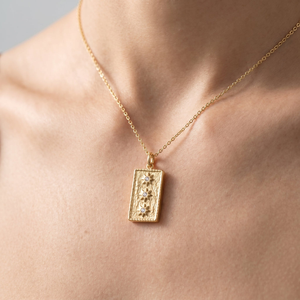 Charm placa con estrellas para collar bañado en oro de 18K puesto, primer plano