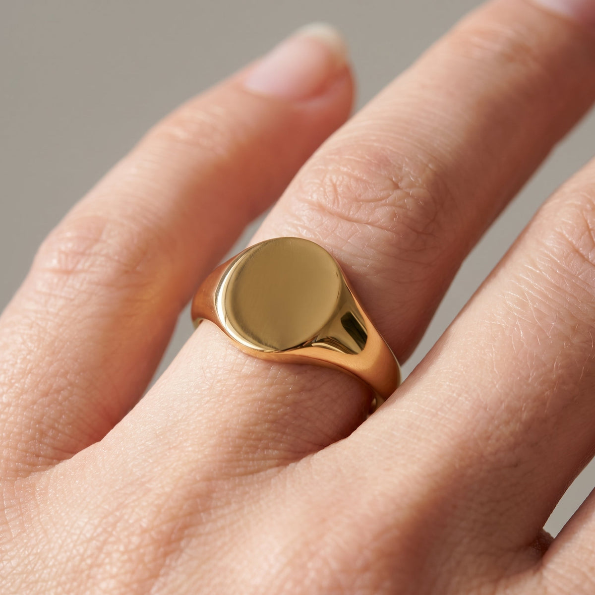 Anillo sello ovalado liso bañado en oro de 18K puesto, primer plano