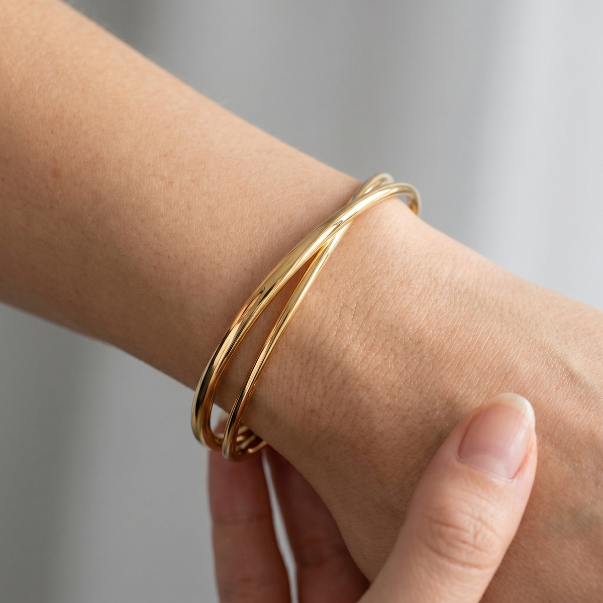 Brazalete rígido cruzado bañado en oro de 18K puesto, primer plano
