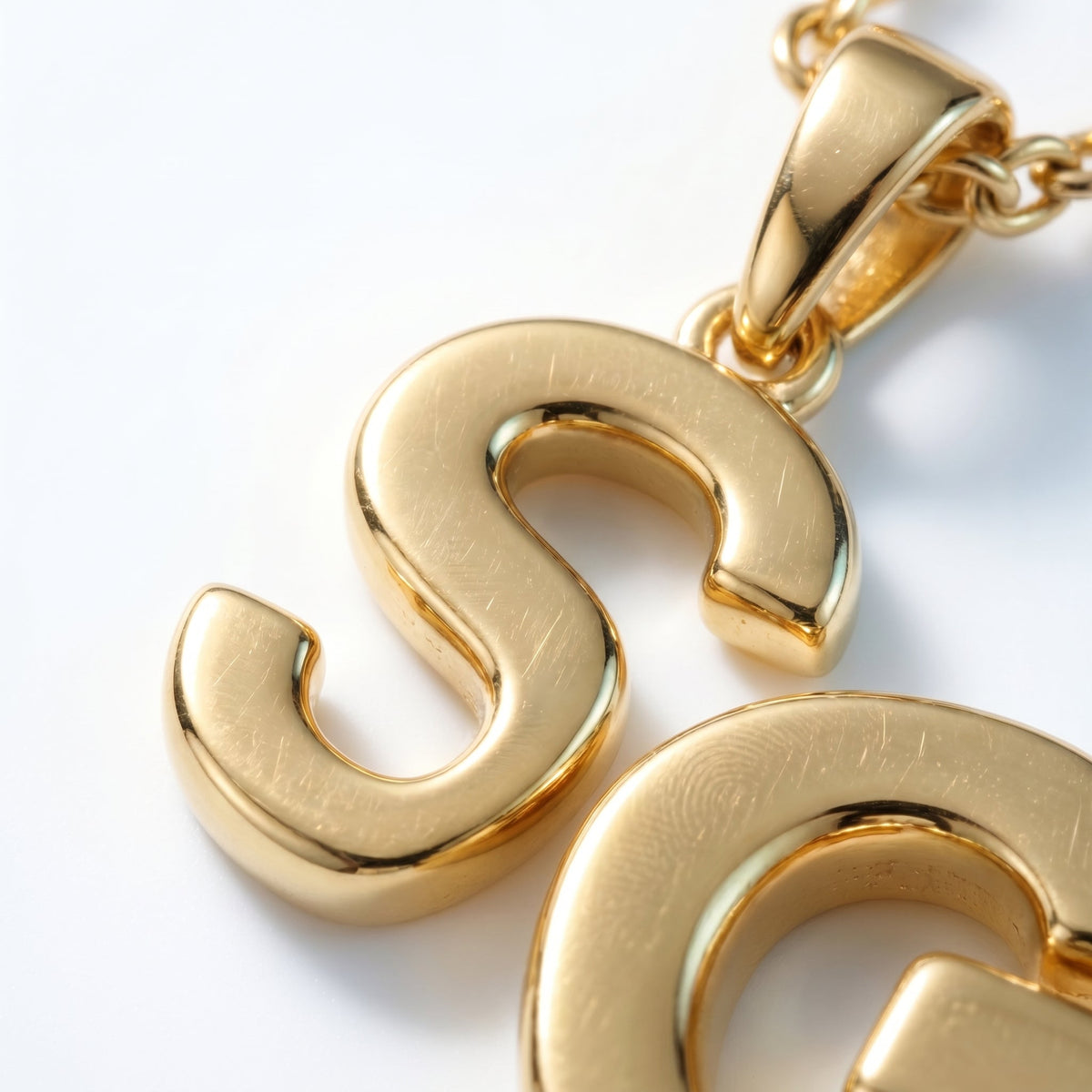 Collar con inicial en cursiva bañado en oro de 18K, detalle de cerca