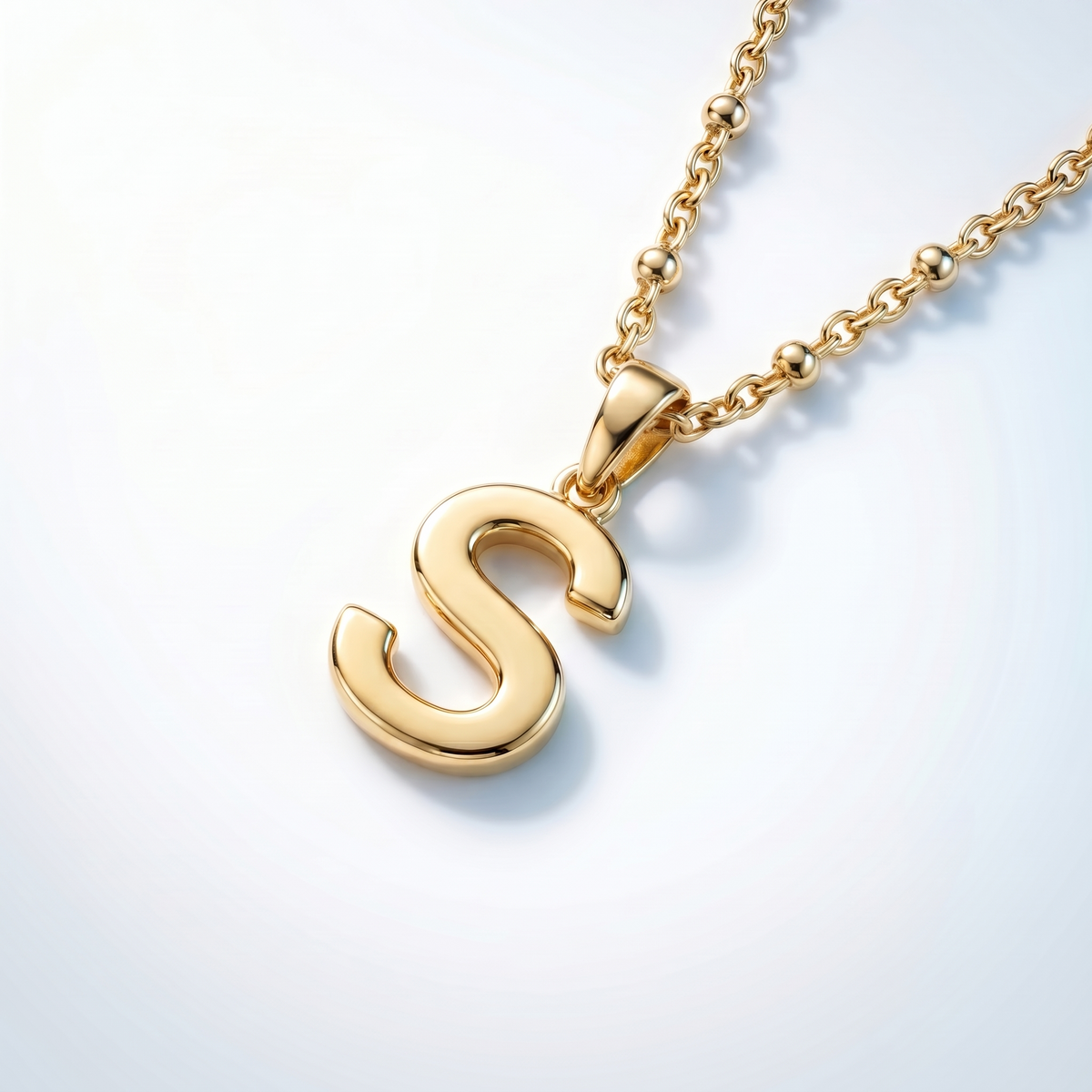 Collar con inicial en cursiva bañado en oro de 18K visto desde arriba