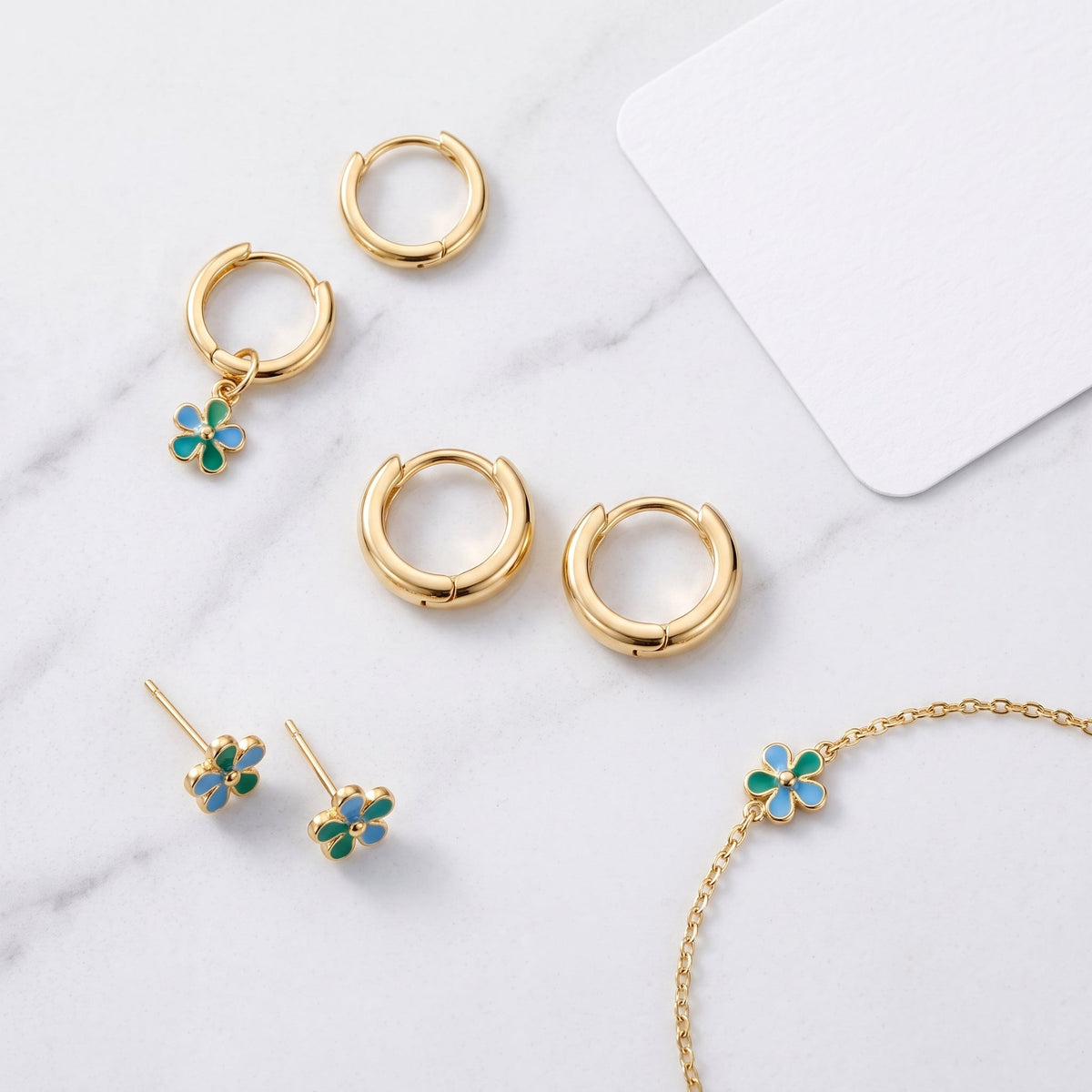 Pendientes huggie lisos bañados en oro de 18K combinados con otras joyas UpperEast