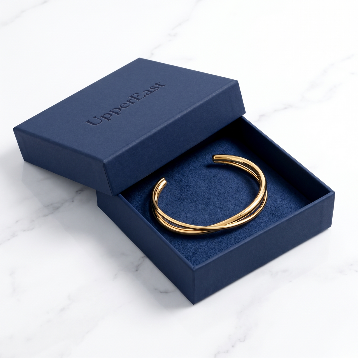 Brazalete rígido cruzado bañado en oro de 18K en el estuche UpperEast