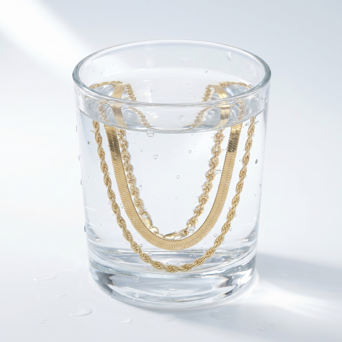 Collar doble espiga bañado en oro de 18K en un vaso de agua