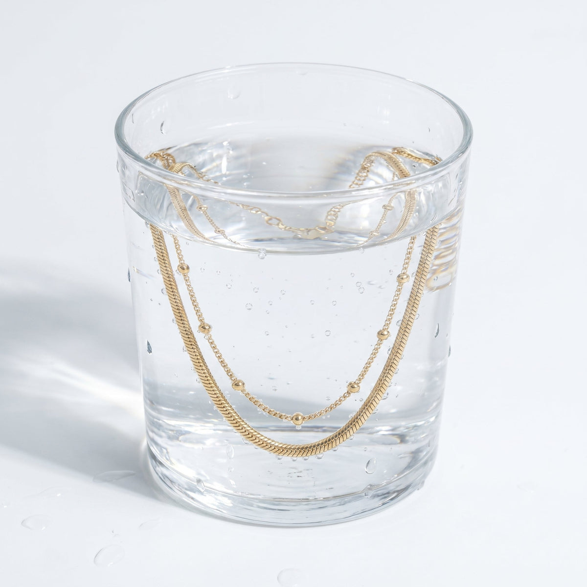 Tobillera doble en capas bañada en oro de 18K en un vaso de agua