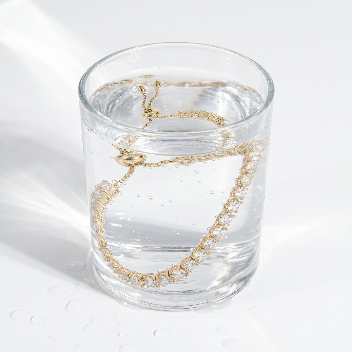 Pulsera tennis ajustable bañada en oro de 18K en un vaso de agua