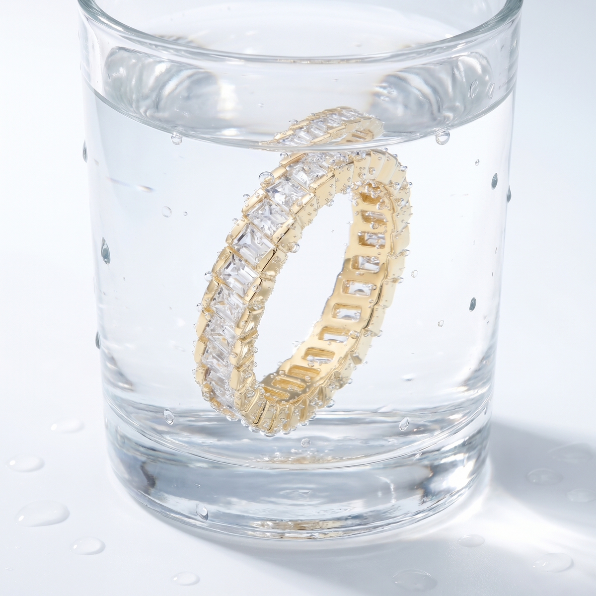 Anillo eternity con circonitas talla princesa bañado en oro de 18K en un vaso de agua