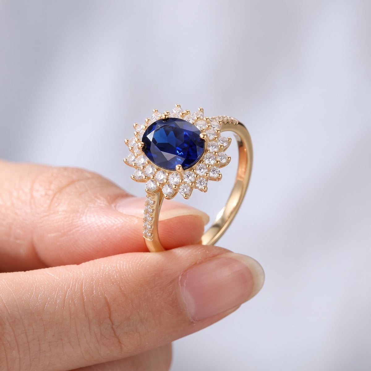 Anello con pietra blu e zirconi placcato oro 18K tenuto tra le dita, per vedere le dimensioni reali