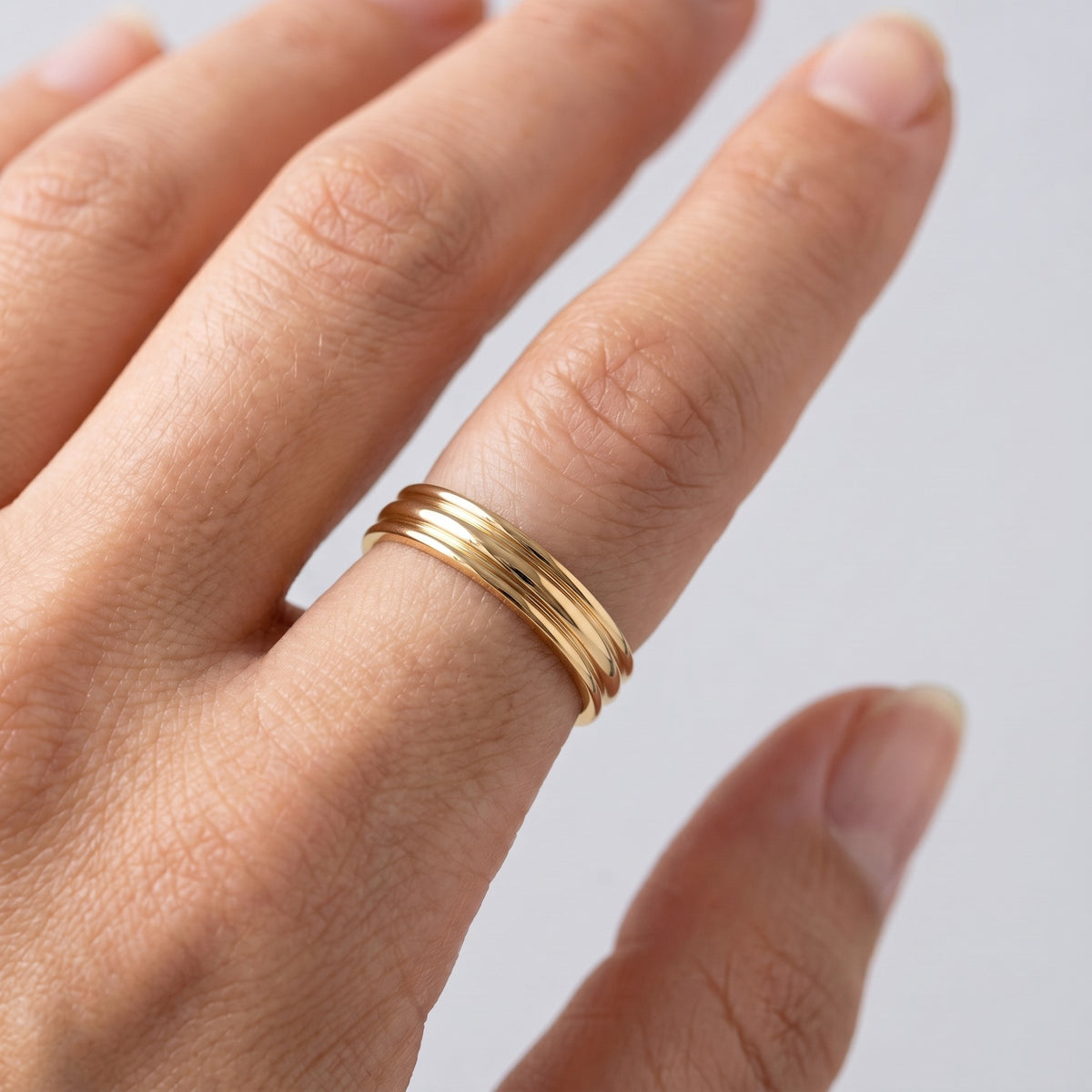 Anello triplo da cerimonia placcato oro 18K indossato, primo piano