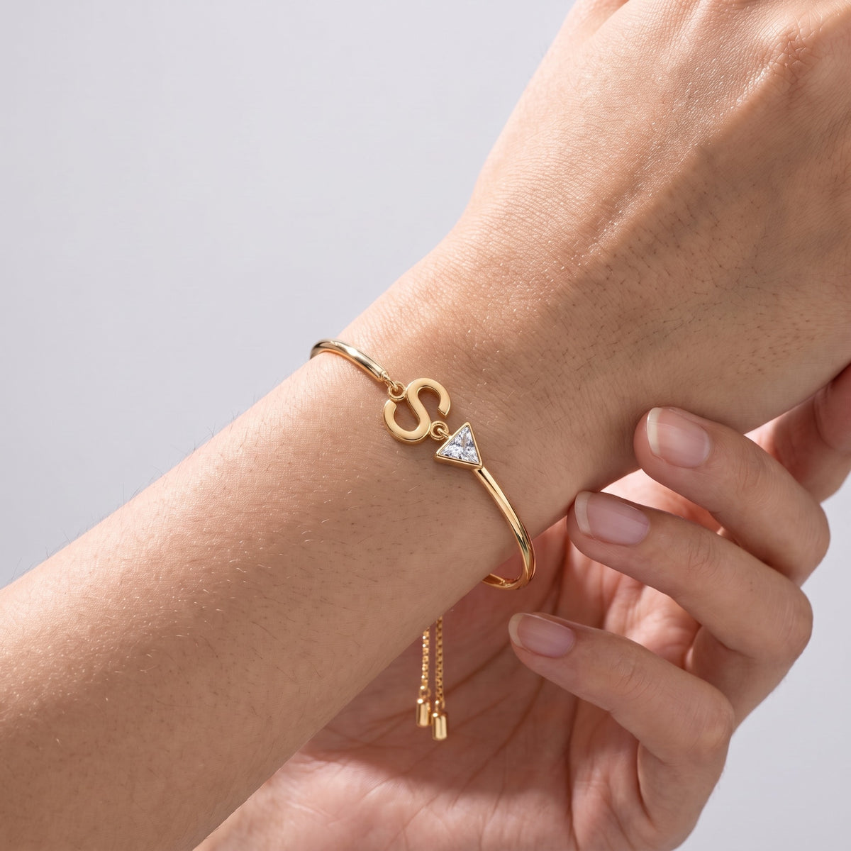 Pulsera con inicial y cristal bañada en oro de 18K puesta, primer plano