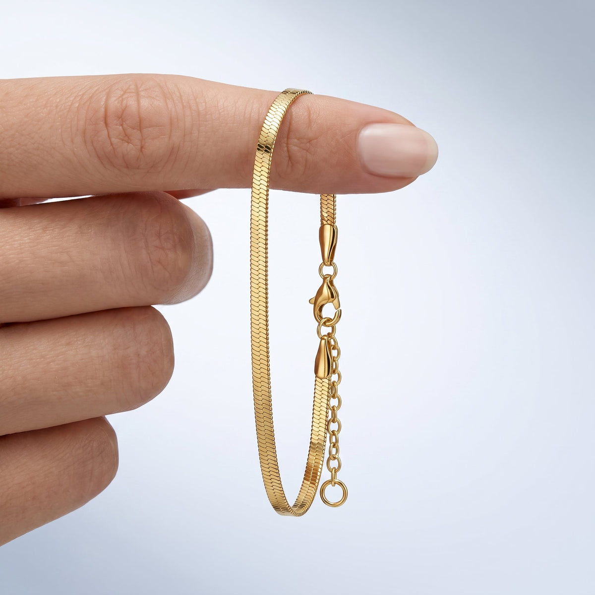 Bracciale catena snake piatta placcato oro 18K tenuto tra le dita, per vedere le dimensioni reali