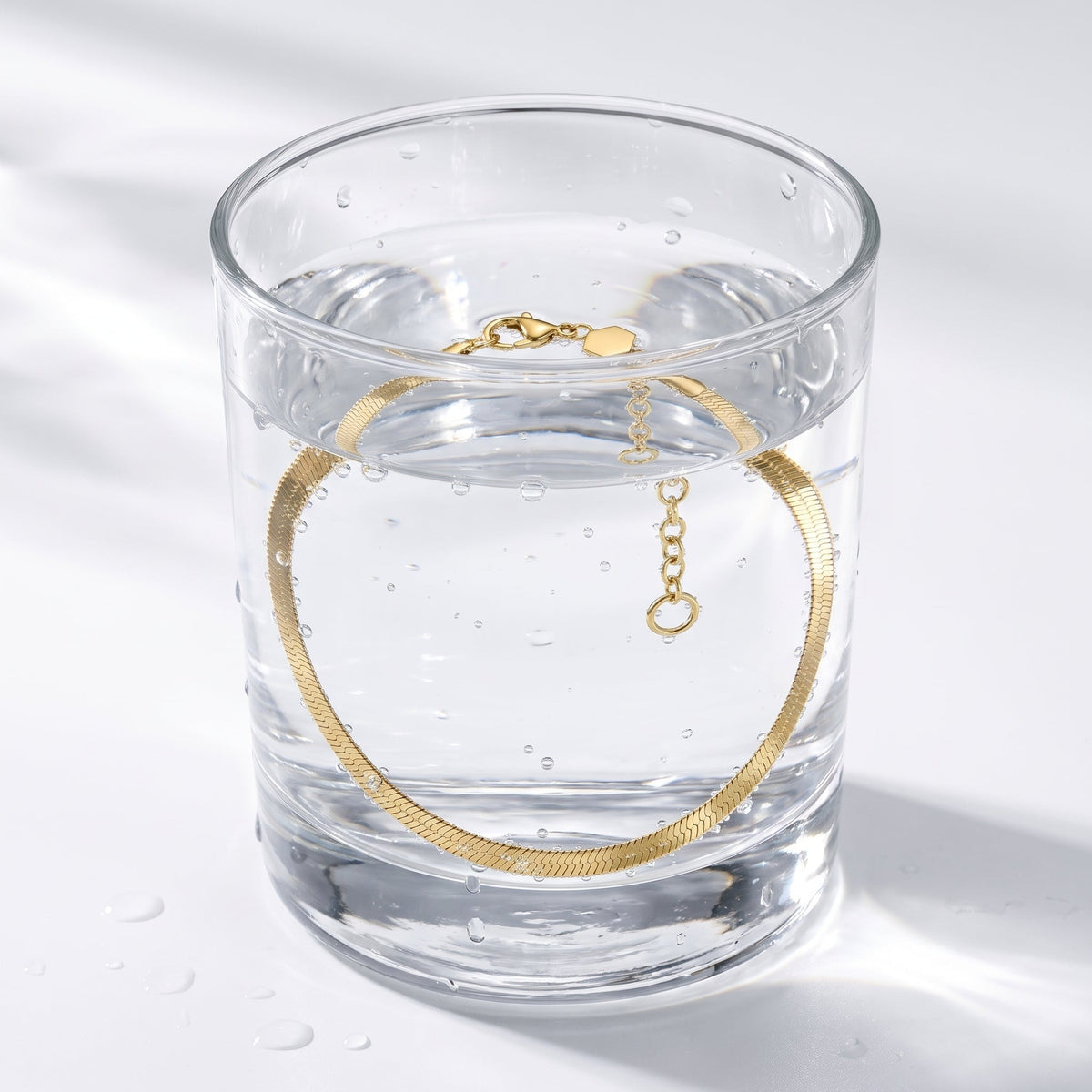 Bracciale catena snake piatta placcato oro 18K in un bicchiere d'acqua