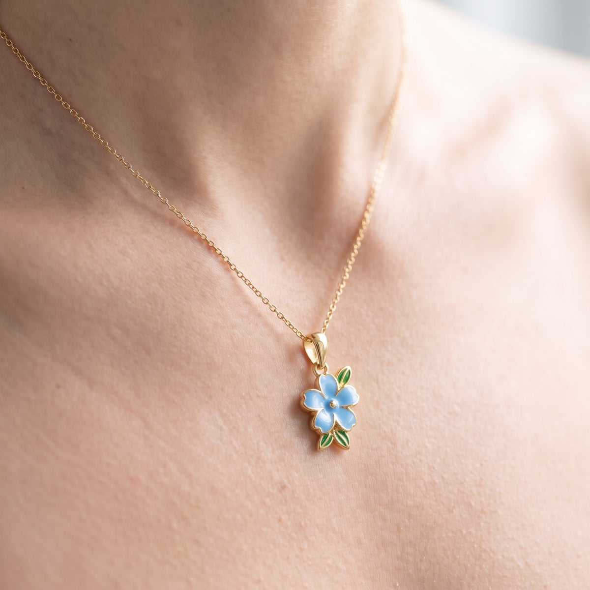 Collar con flor esmaltada azul bañado en oro de 18K puesto, primer plano