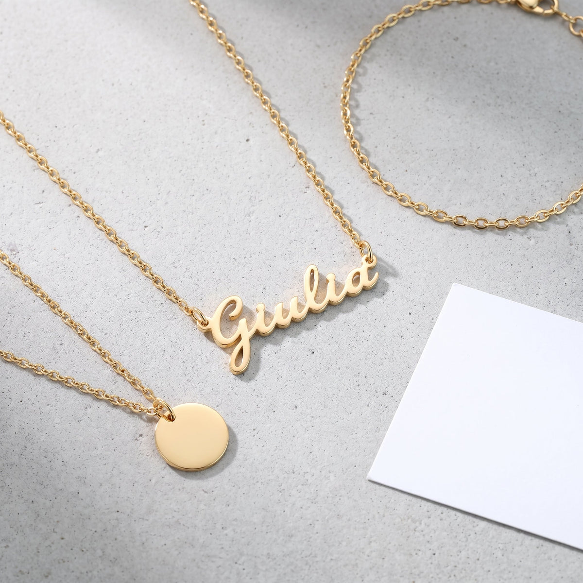Collar con nombre en cursiva bañado en oro de 18K combinado con otras joyas UpperEast