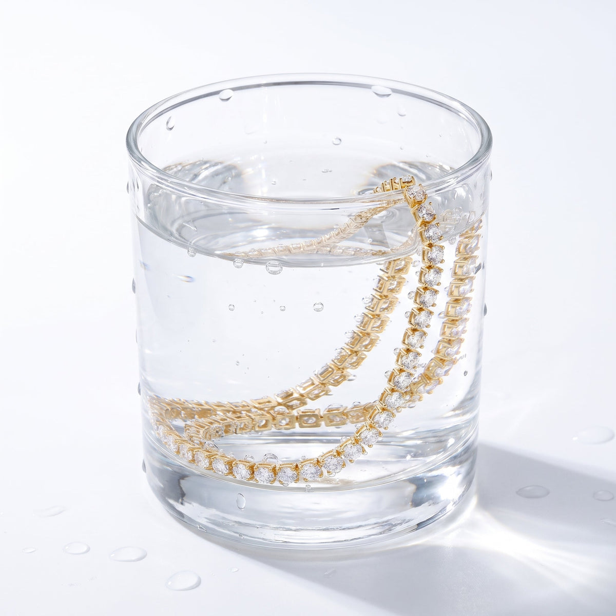 Collar tennis de circonitas bañado en oro de 18K en un vaso de agua