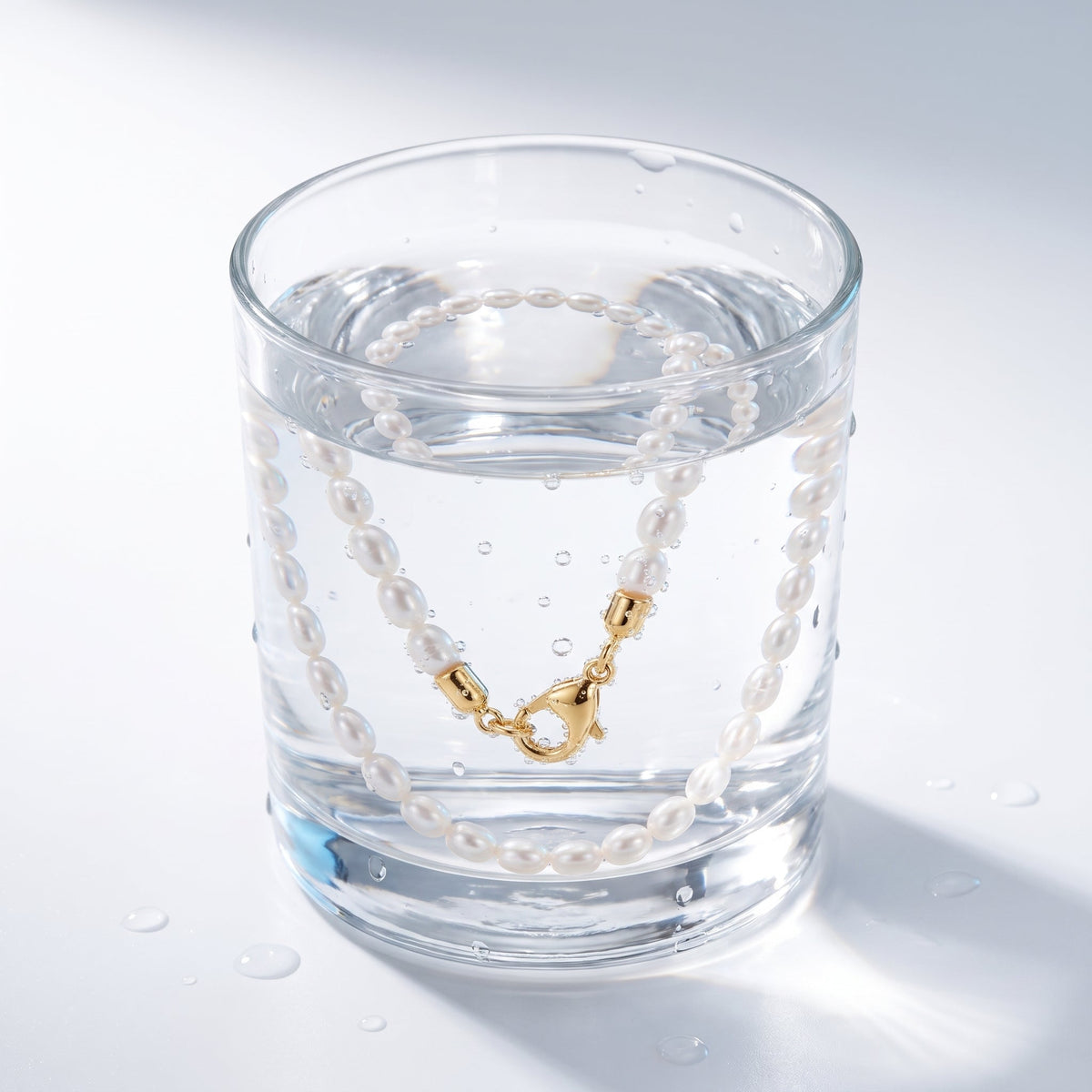 Gargantilla de perlitas bañada en oro de 18K en un vaso de agua
