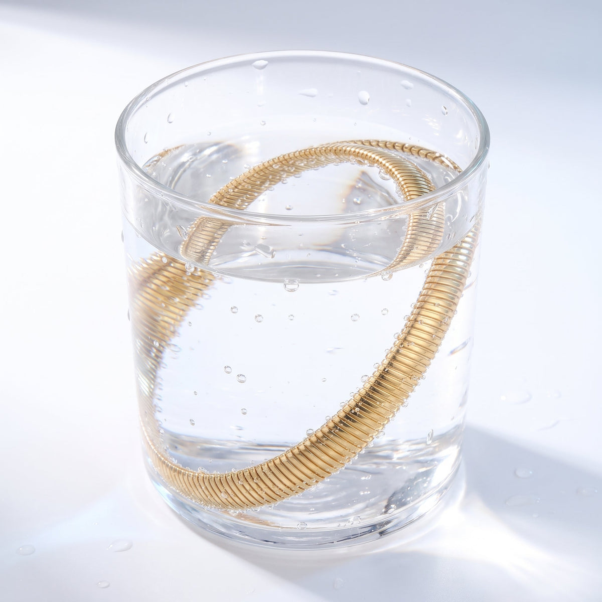 Gargantilla tubogas bañada en oro de 18K en un vaso de agua