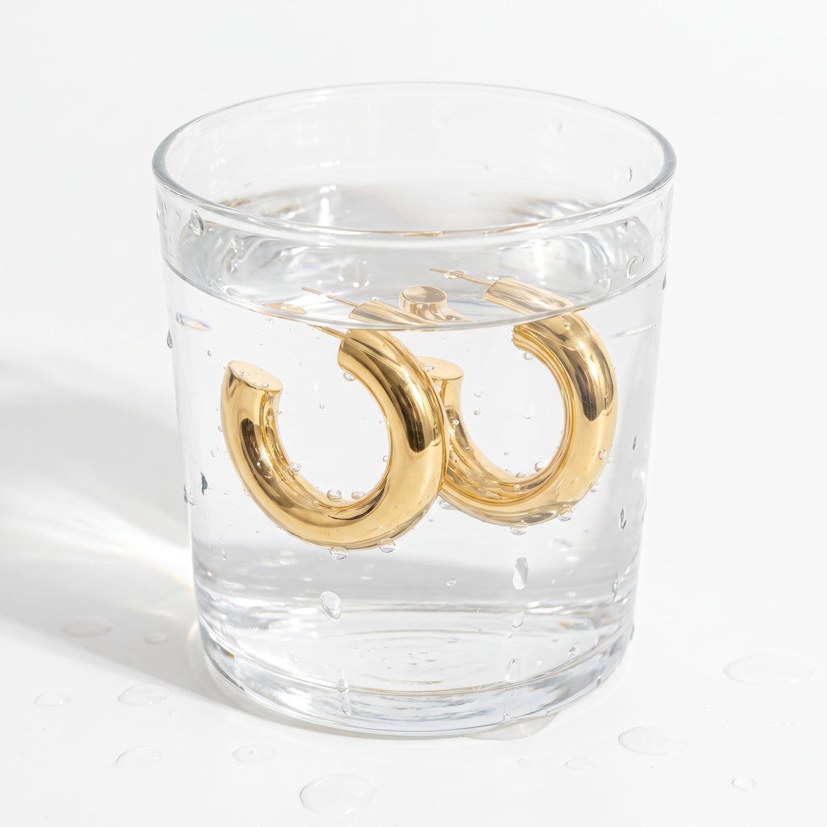 Pendientes de aro gruesos chunky bañados en oro de 18K en un vaso de agua
