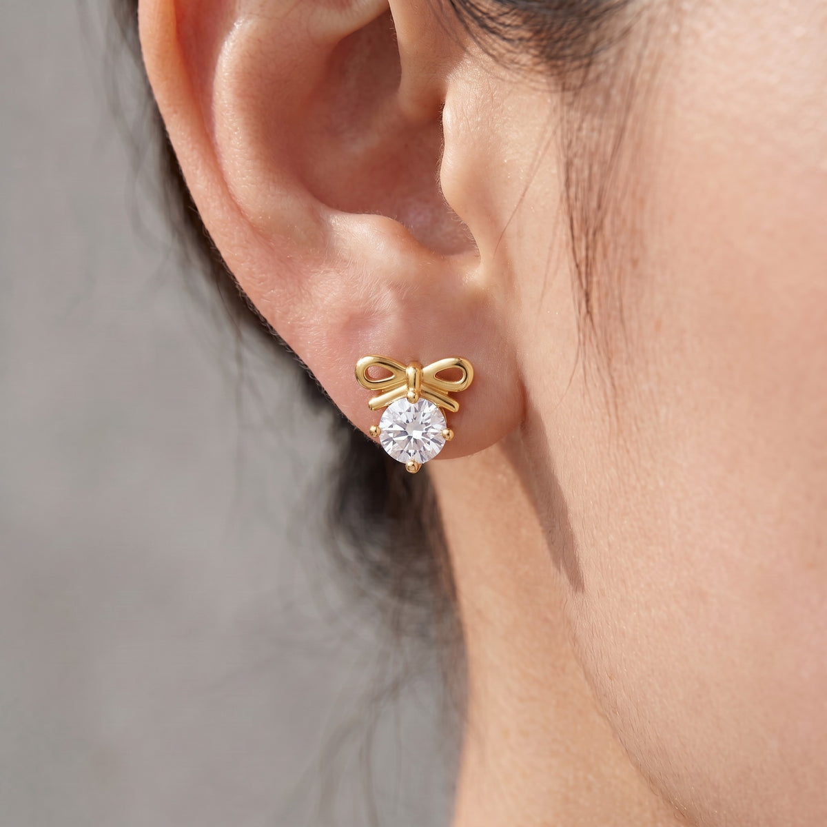 Orecchini fiocco con cristallo placcati oro 18K indossati, primo piano