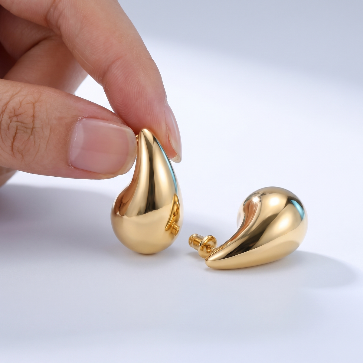 Orecchini goccia bombata leggeri placcati oro 18K tenuti tra le dita, per vedere le dimensioni reali