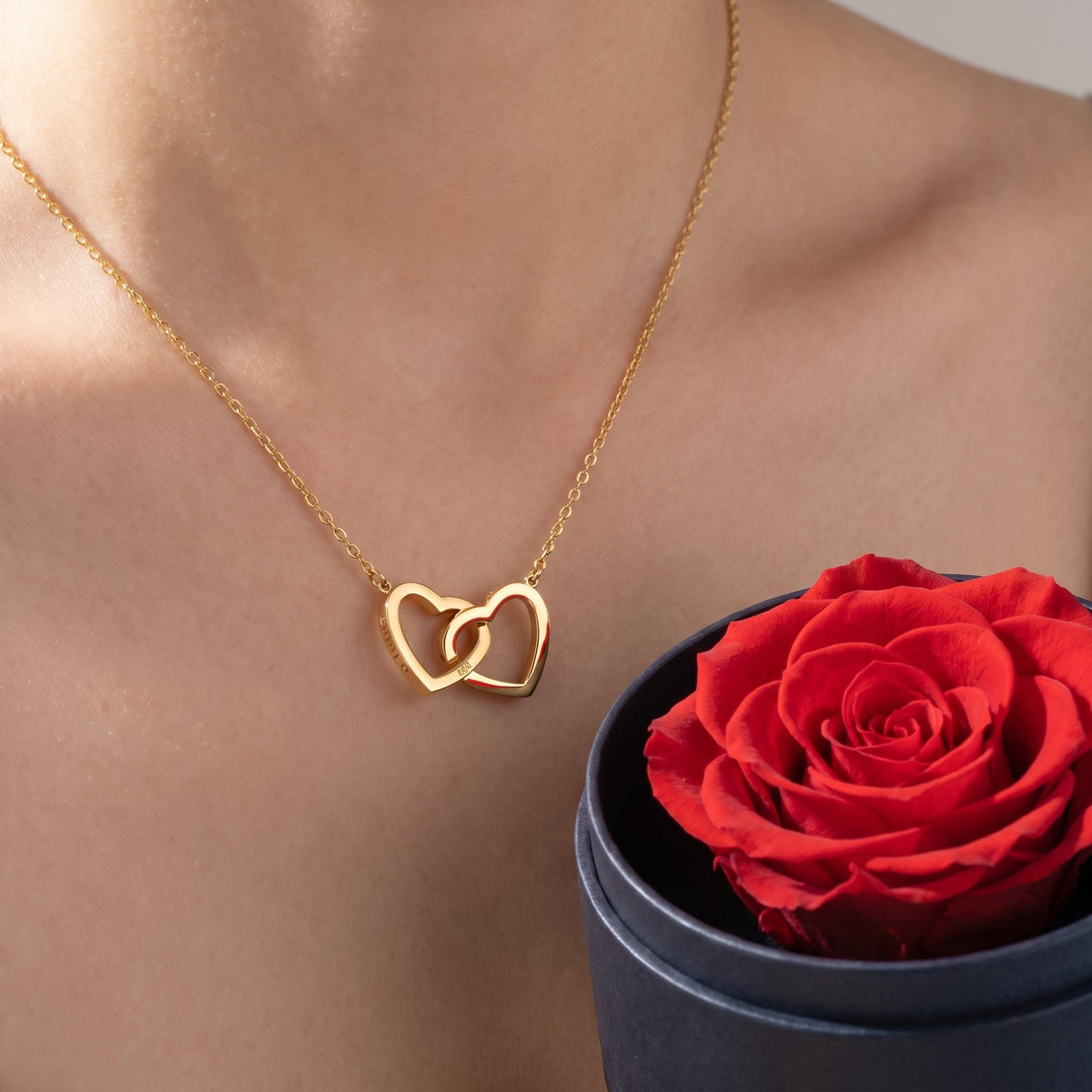 Set regalo de rosa preservada y collar de corazones puesto, primer plano