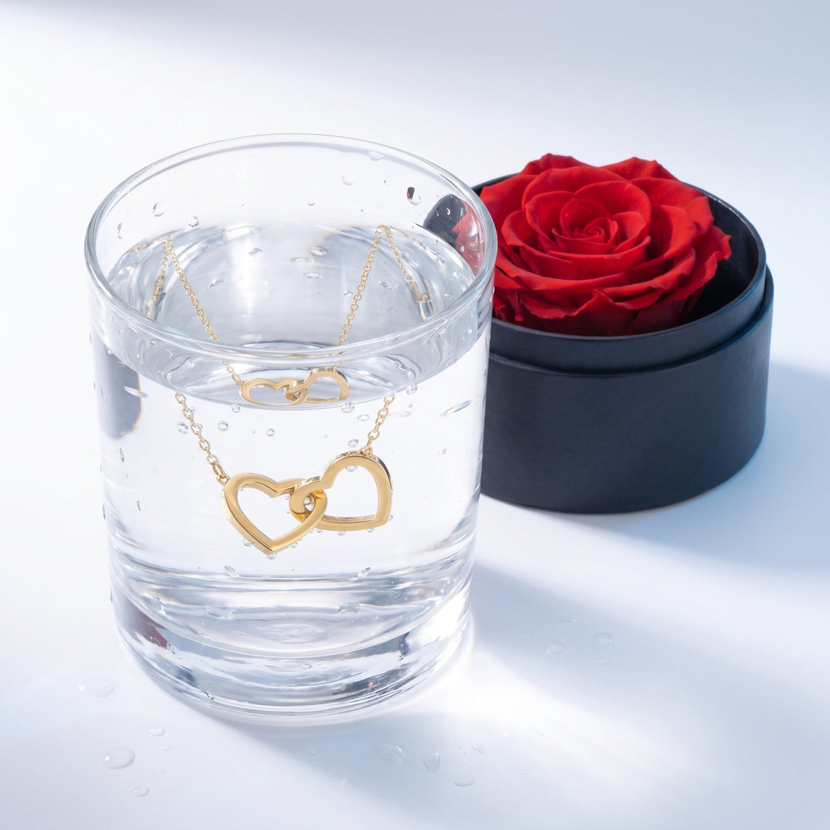 Set regalo de rosa preservada y collar de corazones en un vaso de agua
