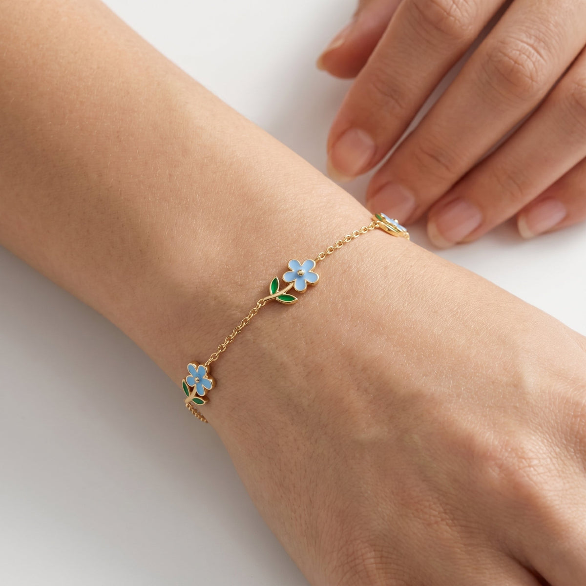 Pulsera con flores azules bañada en oro de 18K puesta, primer plano