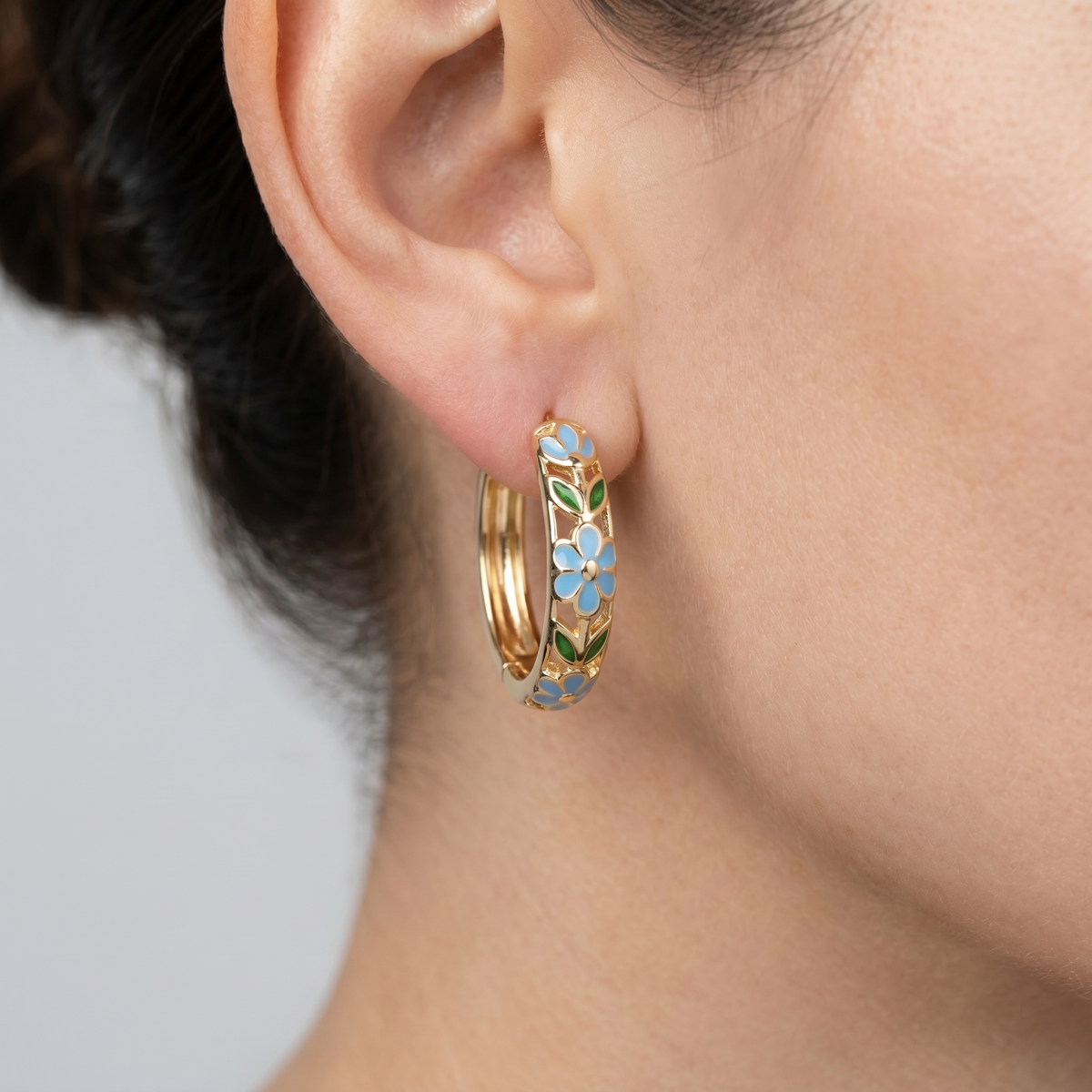 Pendientes de aro con flores bañados en oro de 18K puestos, primer plano