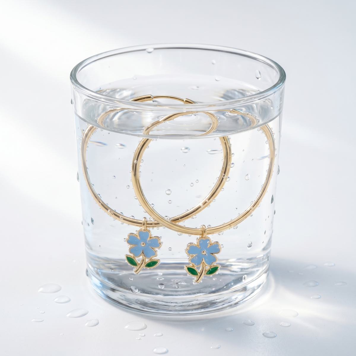 Pendientes de aro maxi con flores bañados en oro de 18K en un vaso de agua