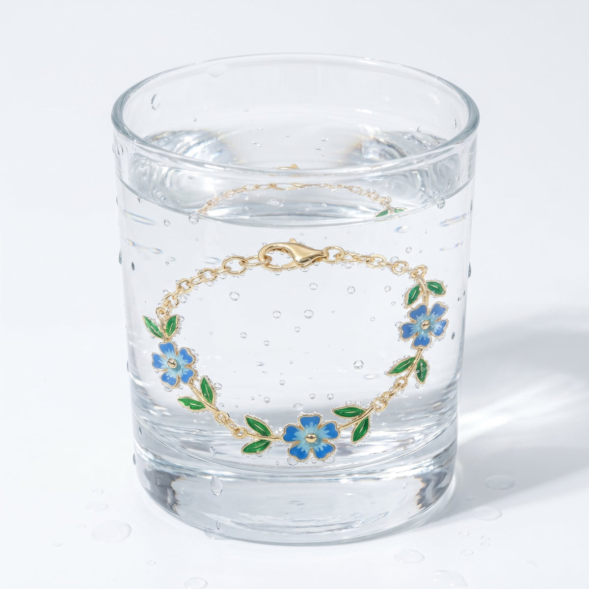 Pulsera círculo con flor bañada en oro de 18K en un vaso de agua