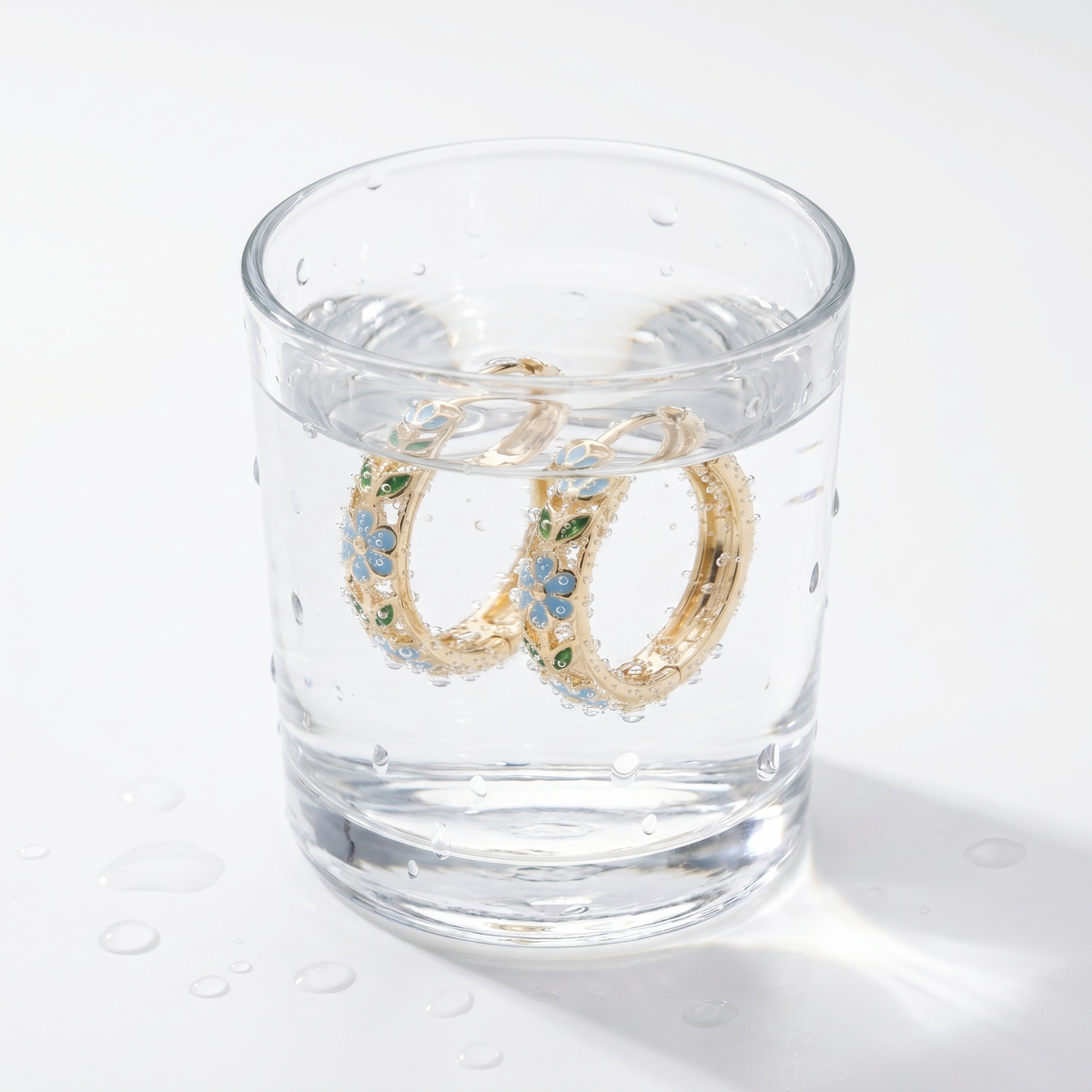 Pendientes de aro con flores bañados en oro de 18K en un vaso de agua