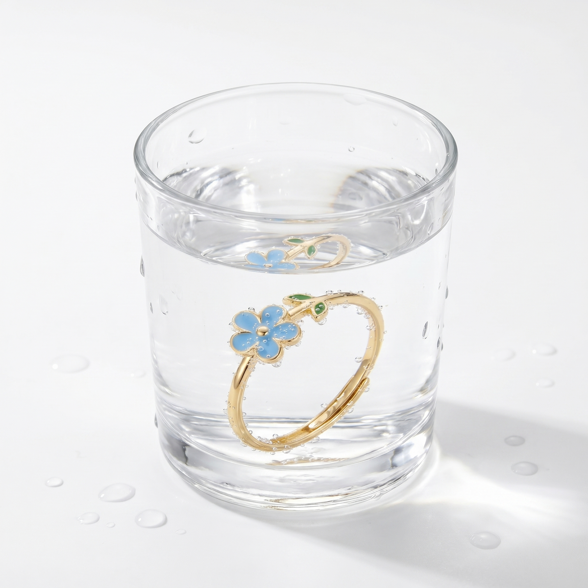 Anillo flor ajustable bañado en oro de 18K en un vaso de agua