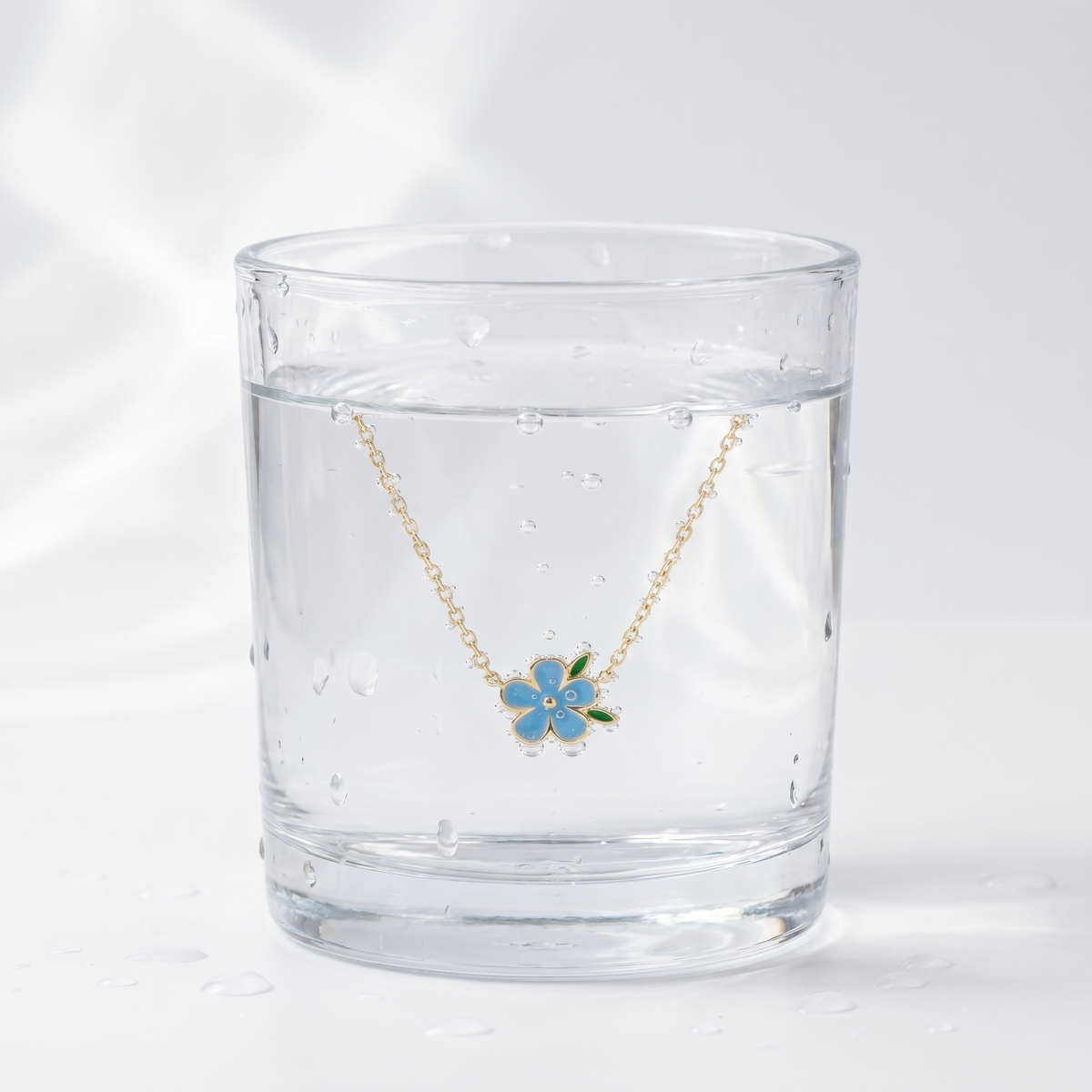 Collar círculo con flor bañado en oro de 18K en un vaso de agua