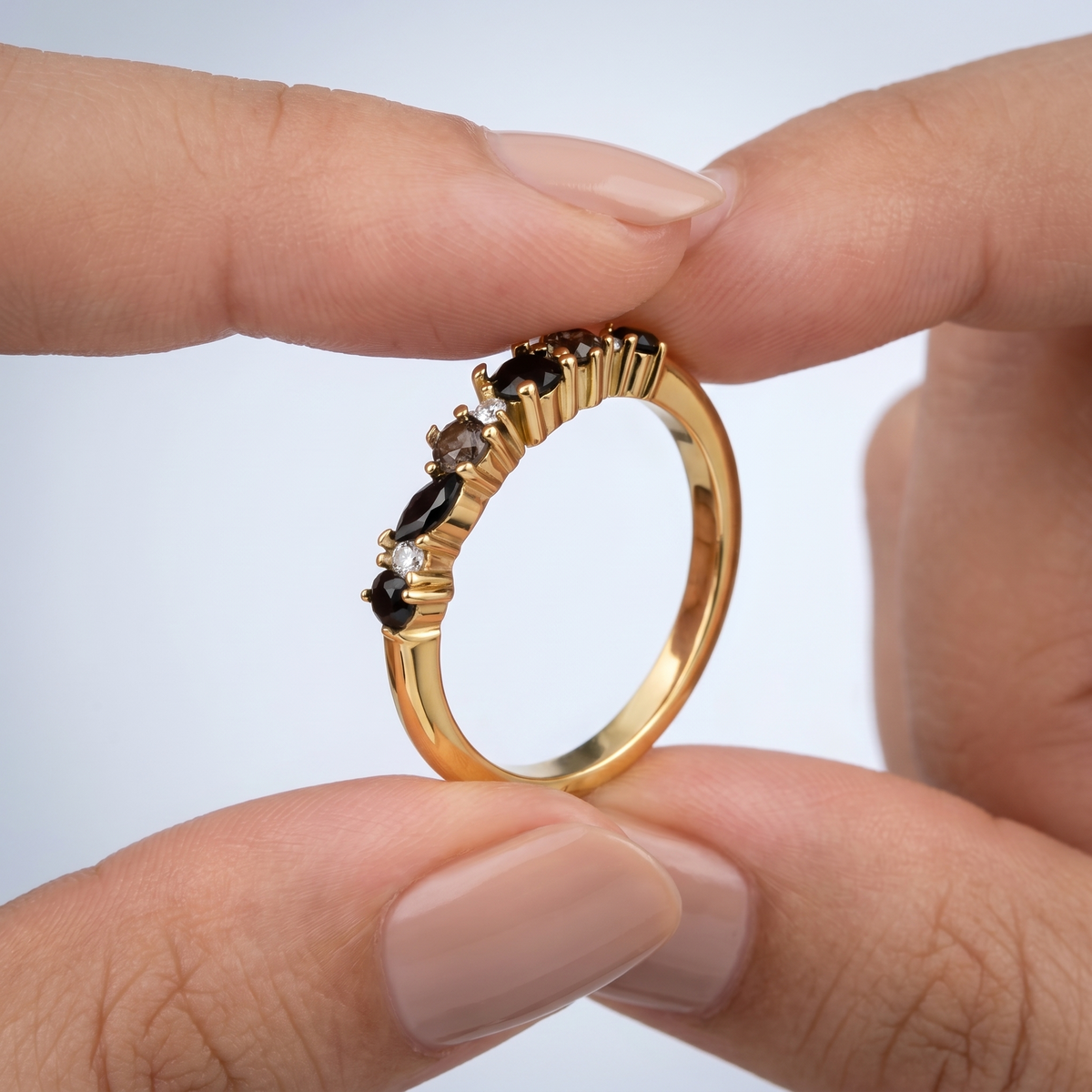 Anillo eternity de obsidiana negra bañado en oro de 18K sostenido entre los dedos, para ver el tamaño real