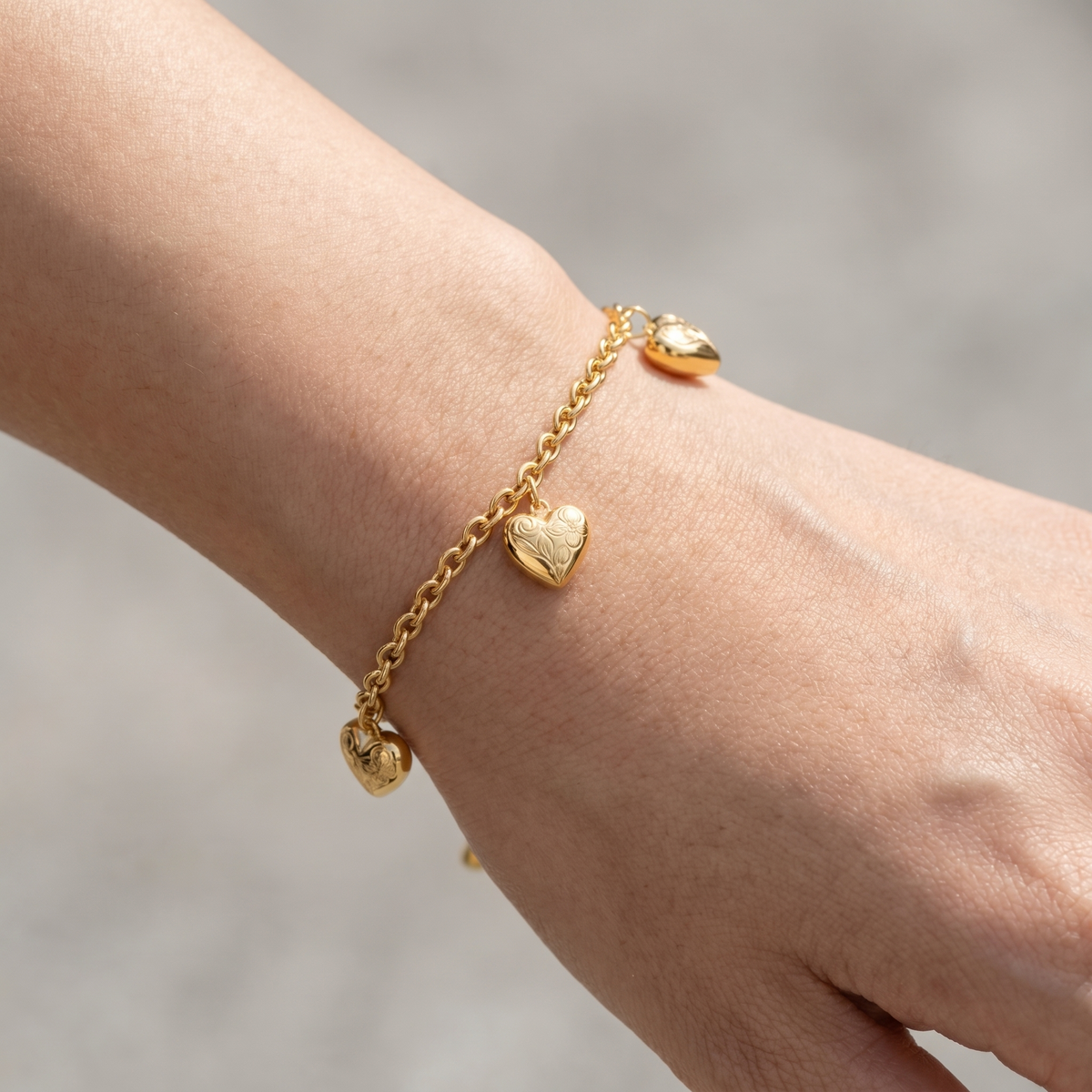 Pulsera con charms de corazones bañada en oro de 18K puesta, primer plano