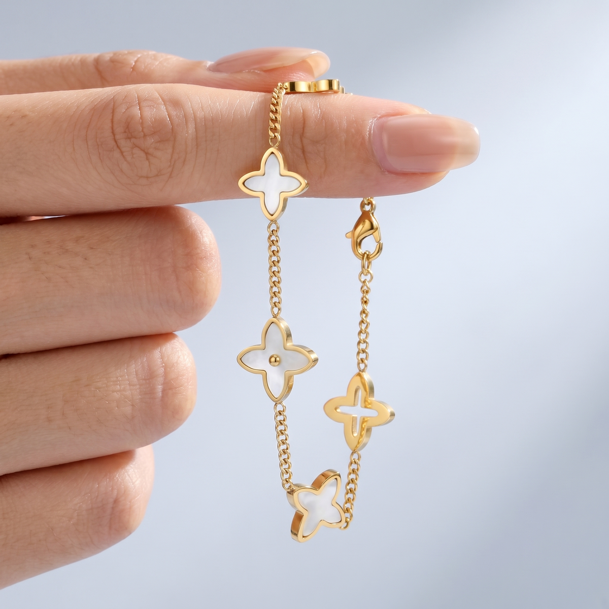 Bracciale quadrifoglio madreperla placcato oro 18K tenuto tra le dita, per vedere le dimensioni reali