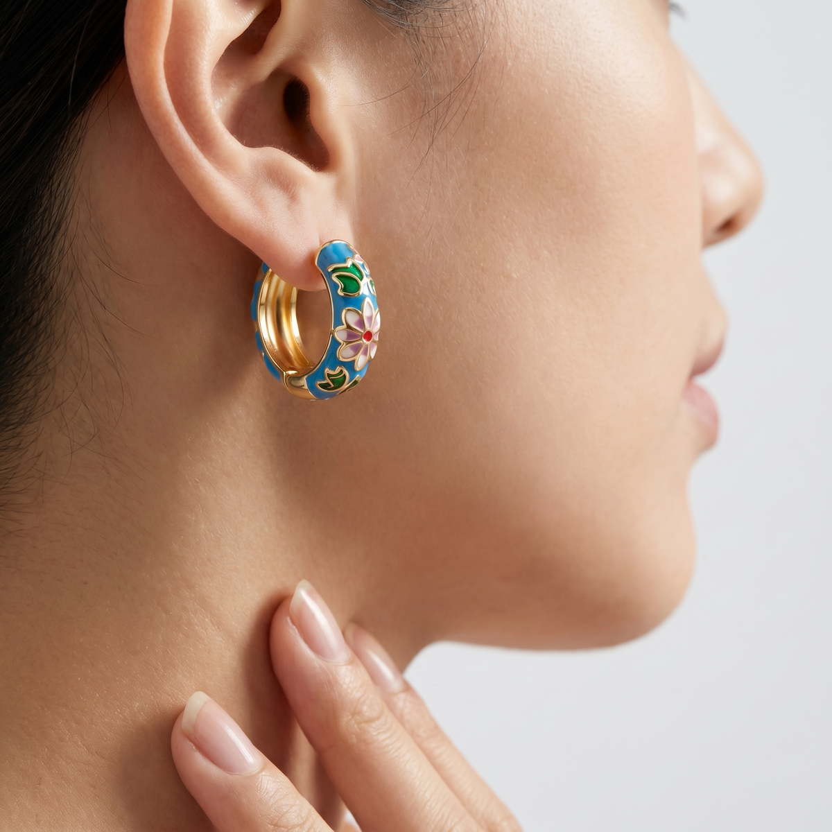 Pendientes flor cloisonné bañados en oro de 18K puestos, primer plano