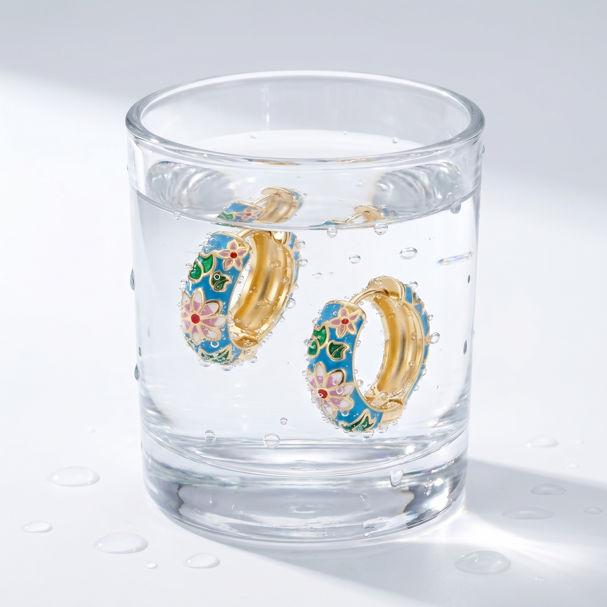 Pendientes flor cloisonné bañados en oro de 18K en un vaso de agua