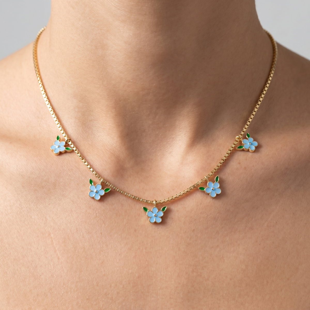 Collana con fiori smaltati azzurri placcata oro 18K indossata, primo piano