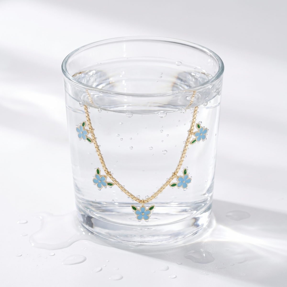 Collana tennis con fiore placcata oro 18K in un bicchiere d'acqua